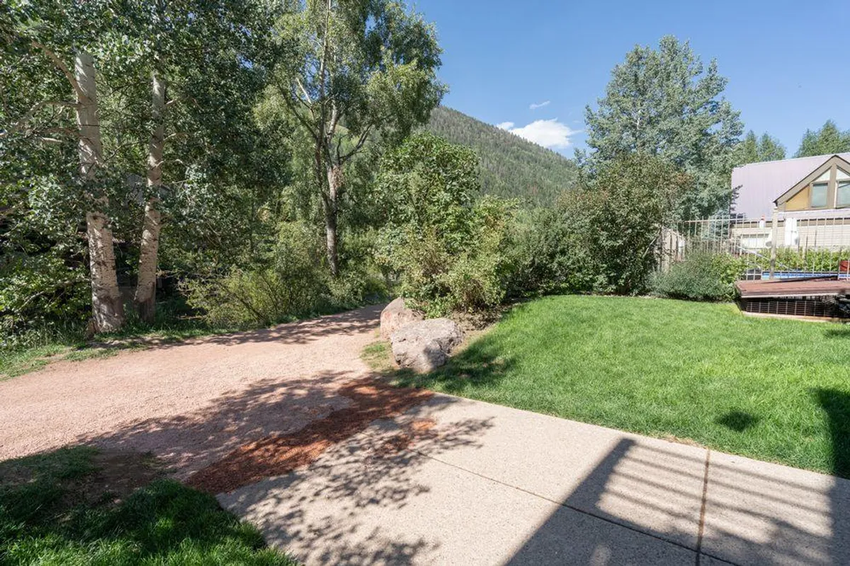 A winding pathway cuts through lush greenery, opening onto a tranquil mountain backdrop. The peaceful setting feels perfect for walking, wildlife spotting, or unwinding after a day of adventure.