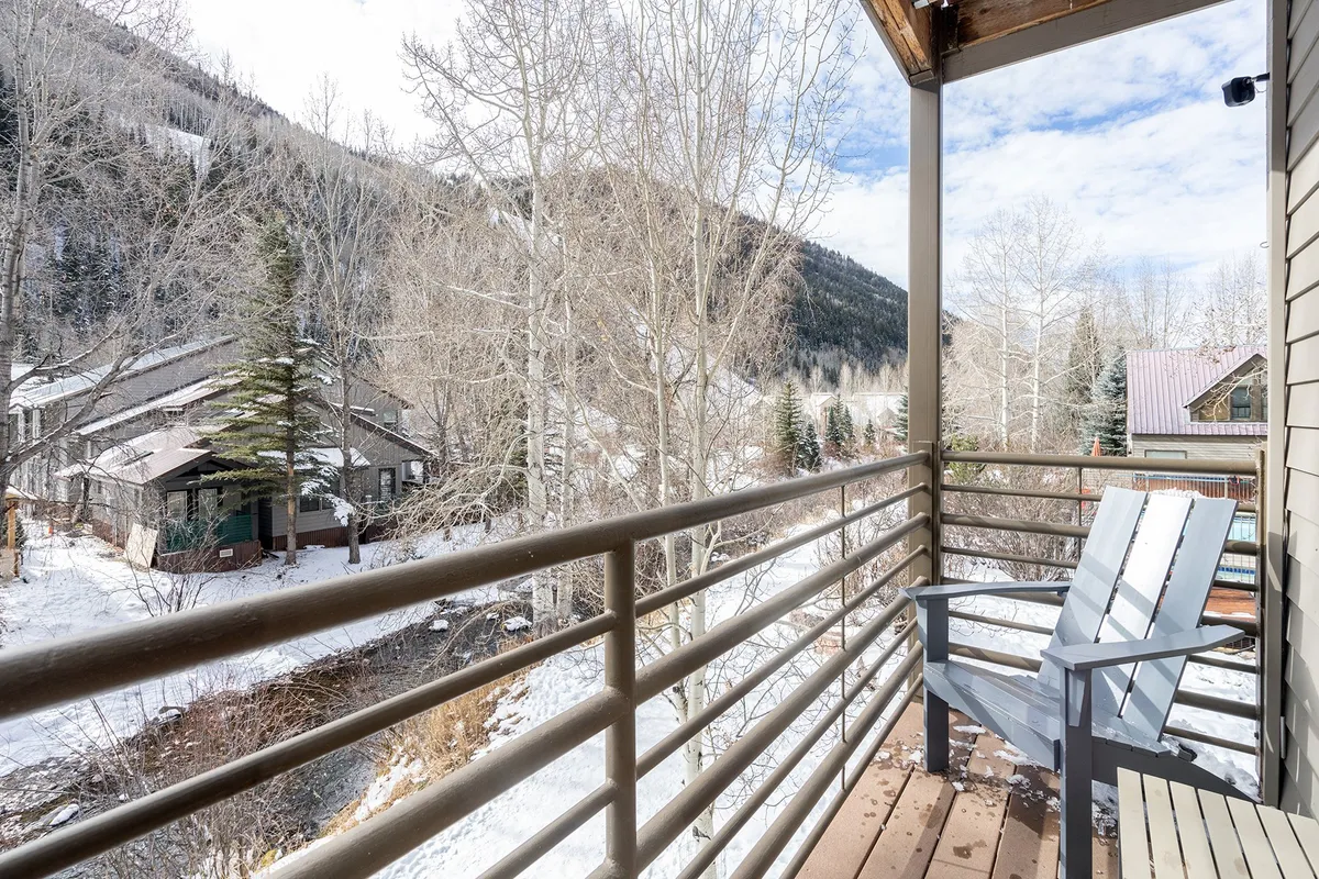 A viewpoint from the balcony with a sitting chair facing out toward snow-laden trees and dramatic mountain scenery. The open railing ensures unobstructed views, and the overall mood is peaceful and contemplative, ideal for enjoying crisp alpine air or unwinding after a day outdoors.