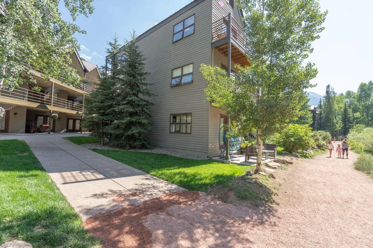 This exterior shot features the building facade and a scenic pathway leading to the property, bordered by vibrant greenery. Balconies offer spots for morning coffee or evening relaxation, and the whole setting feels quiet and inviting.